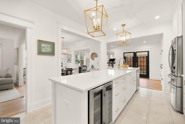 kitchen featuring wine cooler, a notable chandelier, white cabinets, open floor plan, and freestanding refrigerator