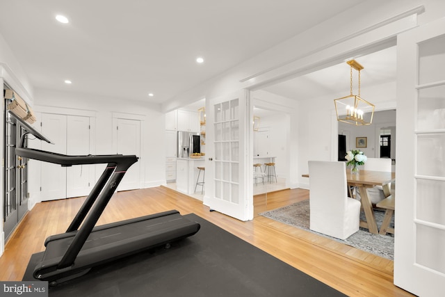 workout area with light wood-style floors, recessed lighting, and an inviting chandelier