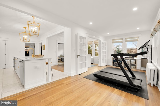 exercise room featuring a chandelier, recessed lighting, baseboards, light wood finished floors, and radiator heating unit