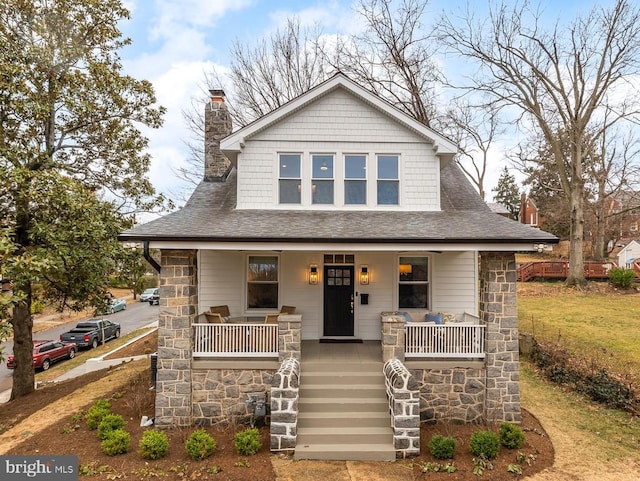 view of front of house with stairs, a porch, a chimney, and a shingled roof