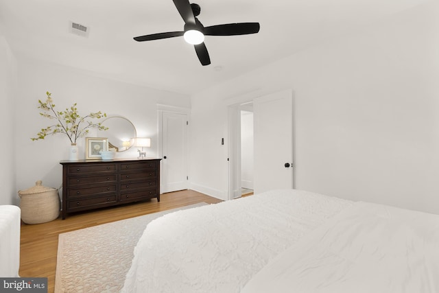 bedroom with a ceiling fan, visible vents, and wood finished floors