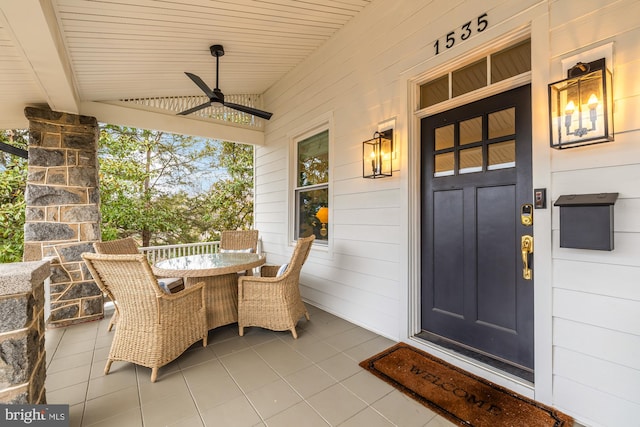 view of exterior entry featuring ceiling fan, a porch, and outdoor dining area