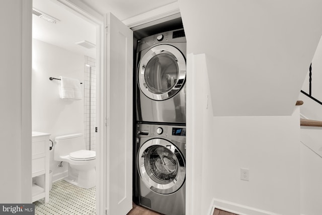 laundry area with stacked washing maching and dryer, baseboards, and visible vents