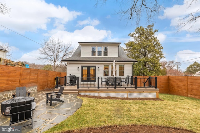 rear view of property featuring french doors, a fenced backyard, a lawn, and a patio