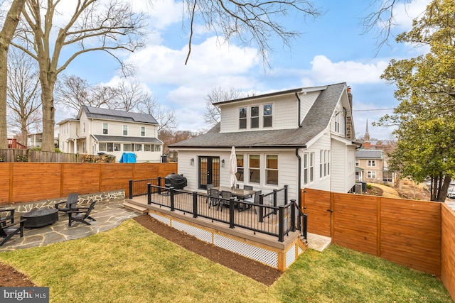 rear view of property featuring a fire pit, a lawn, a fenced backyard, and a wooden deck