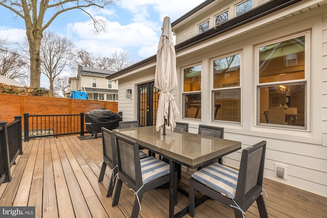 deck featuring fence, outdoor dining area, area for grilling, and french doors