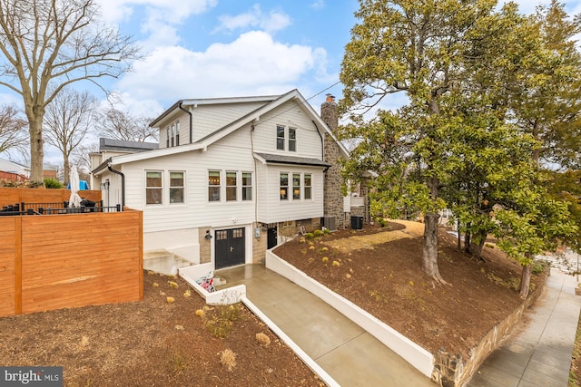 view of front of property with a garage, a chimney, and central air condition unit