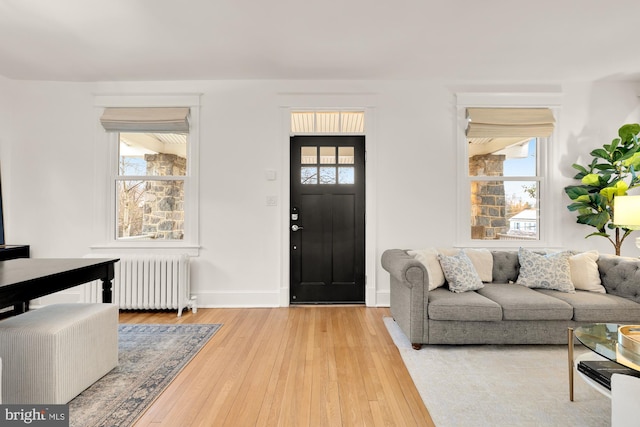 foyer entrance featuring radiator, a healthy amount of sunlight, wood-type flooring, and baseboards