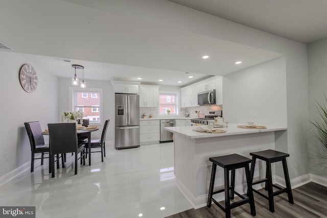 kitchen featuring stainless steel appliances, a wealth of natural light, white cabinets, and a peninsula