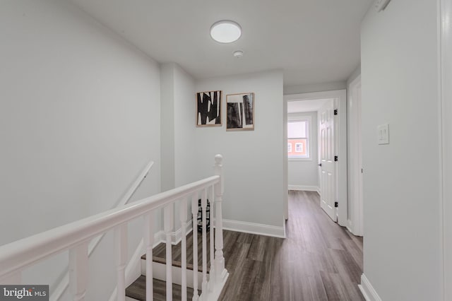 corridor featuring wood finished floors, an upstairs landing, and baseboards