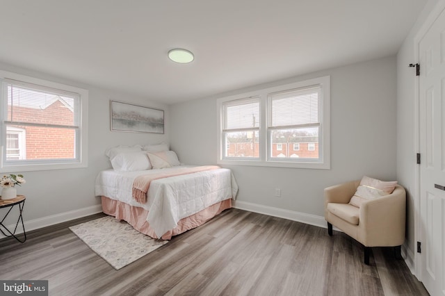 bedroom featuring multiple windows, baseboards, and wood finished floors