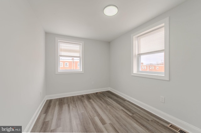 spare room featuring visible vents, baseboards, and wood finished floors