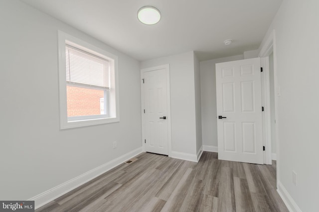 unfurnished bedroom with wood finished floors, visible vents, and baseboards