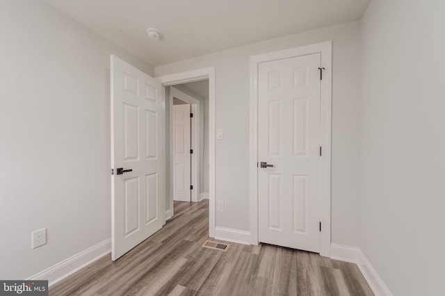 unfurnished bedroom with baseboards, visible vents, and wood finished floors