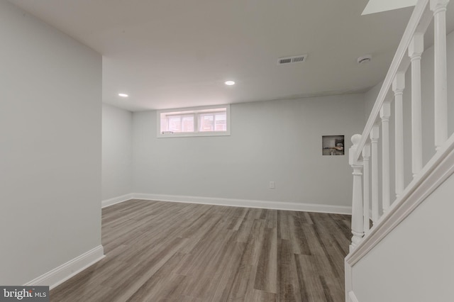 basement featuring baseboards, stairs, visible vents, and wood finished floors