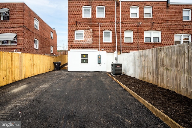 back of house featuring central air condition unit, a fenced backyard, and brick siding