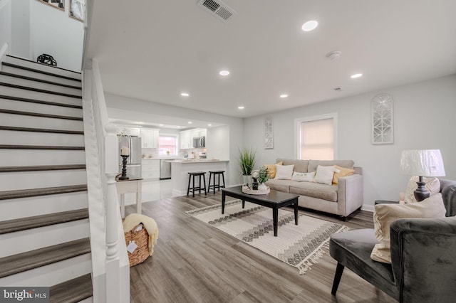 living room featuring light wood-type flooring, stairs, visible vents, and recessed lighting