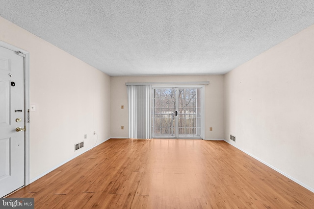 interior space featuring visible vents, baseboards, light wood-style floors, and a textured ceiling