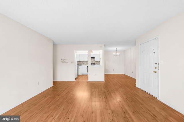 unfurnished living room featuring light wood-style flooring and a chandelier