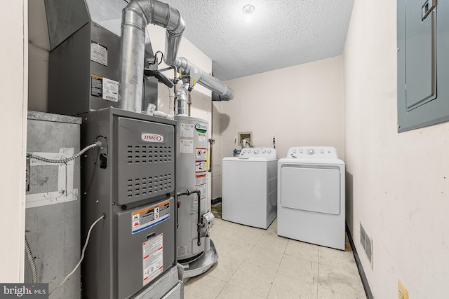 washroom featuring laundry area, electric panel, a textured ceiling, gas water heater, and washer and clothes dryer