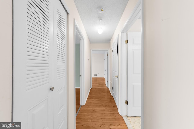 hallway featuring a textured ceiling and light wood-style flooring