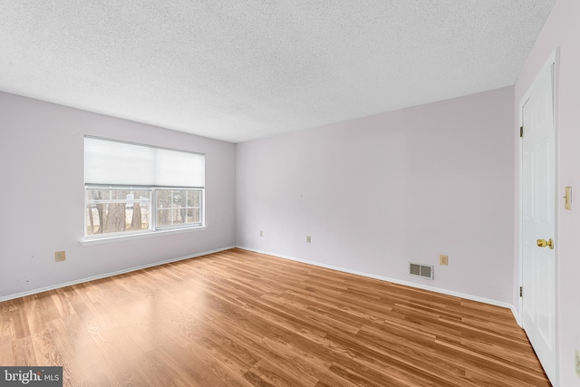 spare room featuring visible vents, a textured ceiling, and wood finished floors