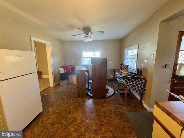 interior space with ceiling fan, freestanding refrigerator, and baseboards