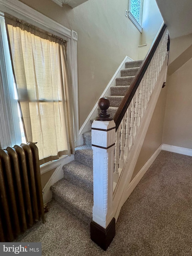 staircase with carpet floors, radiator heating unit, baseboards, and a wealth of natural light