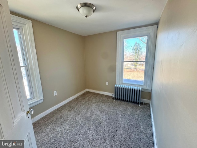 carpeted spare room featuring radiator and baseboards