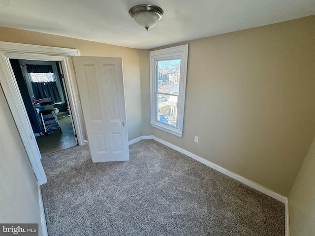 unfurnished bedroom featuring carpet, multiple windows, and baseboards