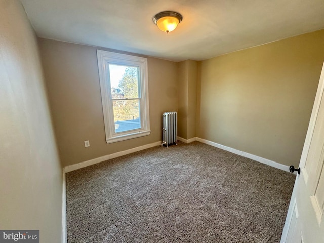 carpeted empty room featuring baseboards and radiator heating unit