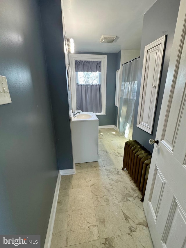 bathroom featuring curtained shower, a sink, baseboards, marble finish floor, and radiator