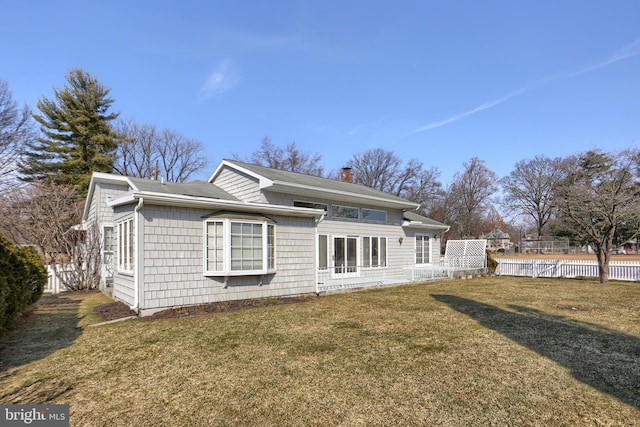 back of property with a yard, a chimney, and fence