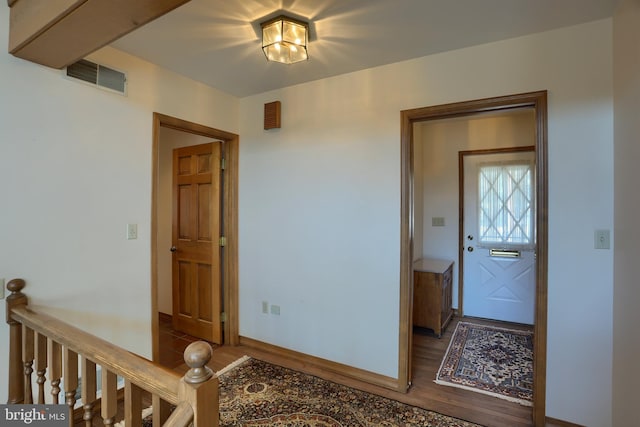 hall with baseboards, visible vents, and wood finished floors