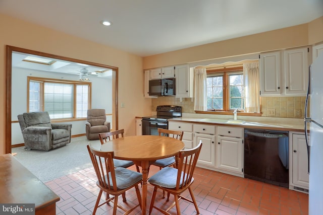 kitchen with black appliances, white cabinets, a sink, and light countertops