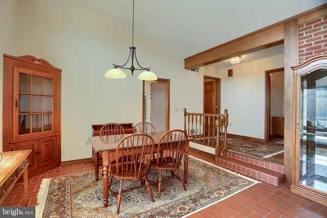 dining area with brick floor, baseboards, and high vaulted ceiling