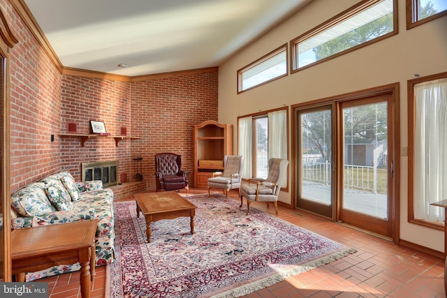 living room featuring brick floor, a fireplace, a towering ceiling, brick wall, and baseboards