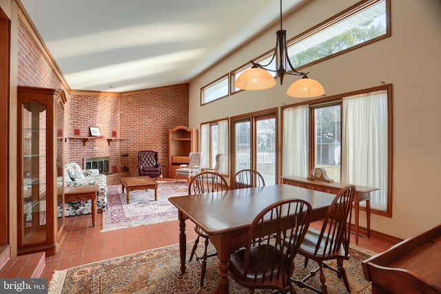 dining area featuring brick floor, a brick fireplace, brick wall, and a high ceiling