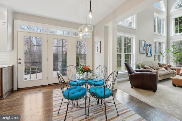 dining room with ornate columns, plenty of natural light, and wood finished floors