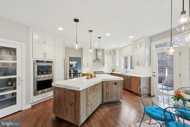 kitchen with white cabinets, decorative backsplash, appliances with stainless steel finishes, dark wood-type flooring, and wall chimney range hood