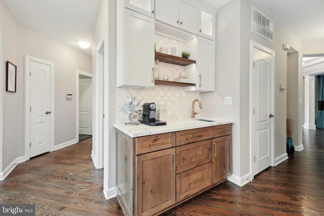 kitchen with dark wood finished floors, open shelves, visible vents, backsplash, and a sink