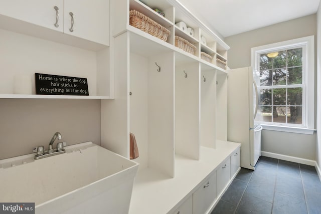 mudroom with dark tile patterned flooring, a sink, and baseboards