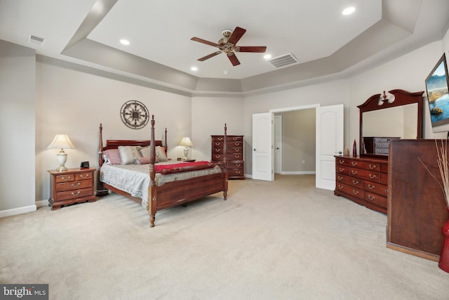 bedroom featuring light carpet, visible vents, a tray ceiling, and baseboards