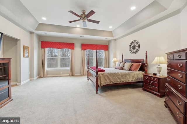 bedroom with recessed lighting, a raised ceiling, light carpet, and baseboards