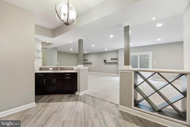 kitchen with baseboards, light countertops, a sink, and open floor plan