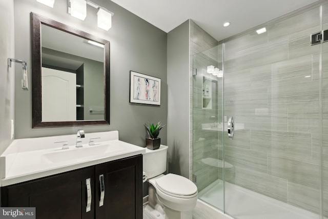 bathroom featuring vanity, a shower stall, and toilet