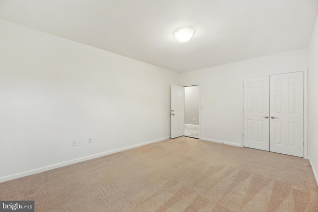 unfurnished bedroom with baseboards, a closet, and light colored carpet