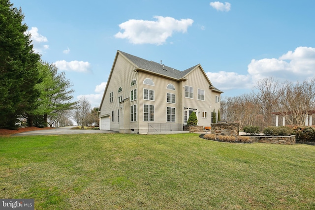 rear view of house featuring a garage, a yard, and aphalt driveway