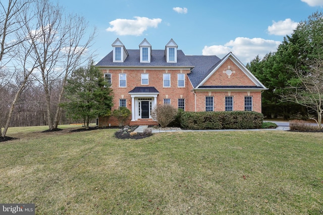 colonial inspired home with brick siding and a front yard