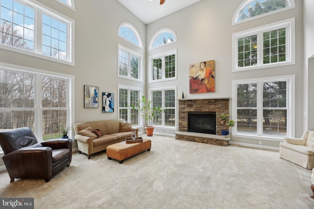 carpeted living area featuring a towering ceiling, a fireplace, and a ceiling fan